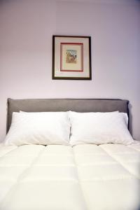 een bed met witte lakens en een foto aan de muur bij Svolio Welcome in Thessaloniki