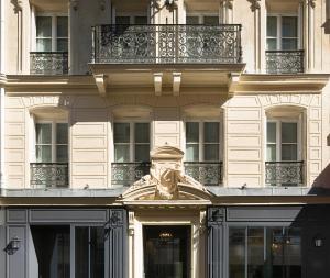 ein Gebäude mit einer Statue auf der Vorderseite in der Unterkunft Les Plumes Hotel in Paris