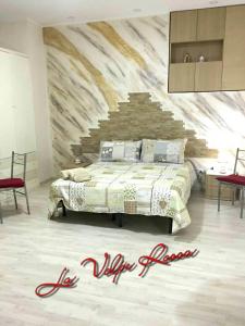 ein Schlafzimmer mit einem Bett und einer Steinmauer in der Unterkunft Bed and Breakfast La Volpe Rossa in Regalbuto
