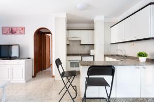 プラヤ・デ・ラス・アメリカスにある"Las dos terrazas": ático en complejo residencialの白いキャビネットと黒い椅子付きのキッチン