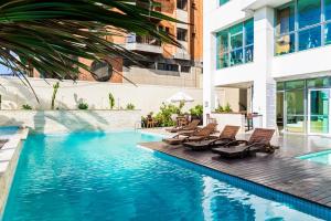 uma piscina com espreguiçadeiras ao lado de um edifício em Mandai Flat Hotel em Cabo Frio