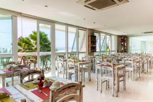 a dining room with tables and chairs and windows at Mandai Flat Hotel in Cabo Frio