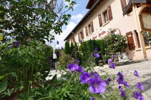 einen Garten mit lila Blumen vor einem Gebäude in der Unterkunft Domaine du Haut Jardin Hôtel & Chalets Spa Privé in Rehaupal