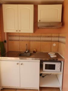 een keuken met witte kasten, een wastafel en een magnetron bij Anse Caritan Mahogany in Caritan