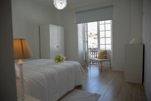 オルタにあるAzores Horta Apartments T0の白いベッドルーム(ベッド1台、椅子付)