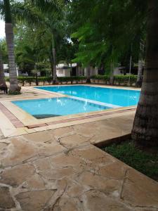 a large blue swimming pool with trees in the background at Royal Palms Apartment A4 in Mombasa