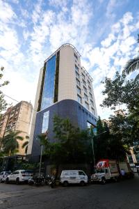 un edificio alto con macchine parcheggiate di fronte di The Empresa Hotel a Mumbai