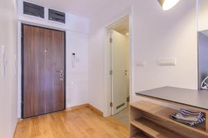 a kitchen with white walls and a wooden door at Sava Smart Apartment in Belgrade