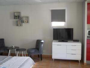 ein Schlafzimmer mit einem TV auf einer Kommode mit einem Stuhl in der Unterkunft STUDIO INDEPENDANT LA TURBIE in La Turbie