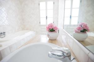 baño con lavabo y 2 jarrones con flores rosas en Villa Vincenza, en Arenella