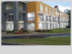 a large yellow building with flowers in front of it at Clarion Pointe Indianapolis Northeast in Castleton