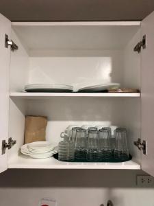 a cupboard with plates and glasses in a kitchen at Baguio Central Apartment by Goshenland in Baguio