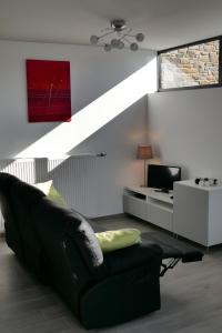 a living room with a black couch and a television at L'Aubépine in Francorchamps