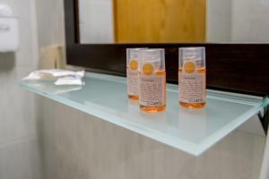 duas garrafas de líquidos cor de laranja sentadas numa mesa de vidro em Hotel Agios Thomas em Ligia