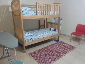 a wooden bunk bed with a red chair and a rug at Family Friendly Stay near Entebbe Airport in Entebbe +6 photos