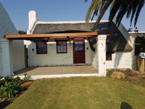 a white house with a red door and a palm tree at Flamingo Cottage no 12 in Meersig