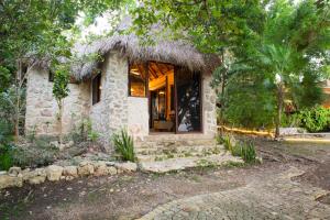 una pequeña casa de piedra con ventana y árboles en Private Bungalow @ Bacalar 7 Colors Lagoon en Bacalar