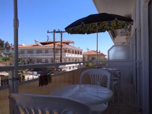 einen Balkon mit einem Tisch und einem Sonnenschirm in der Unterkunft Rooms To Let Giannis in Makrýgialos