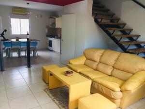 a living room with a yellow couch and a kitchen at Excelente Duplex en Consorcio Privado c/ cochera in San Juan