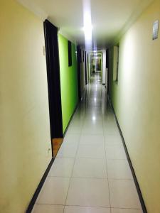 an empty hallway with green walls and white tiles at Hotel Parkway Inn 58 Street in Bogotá