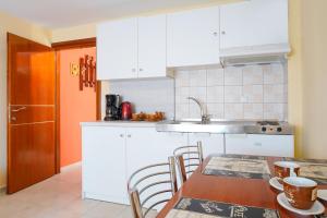 a kitchen with white cabinets and a table with chairs at Thomas Apartments in Skala Marion +47 photos