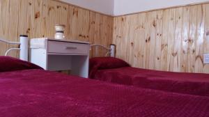 Hospedaje La Serranita في باهيا بلانكا: سريرين في غرفة ذات أغطية أرجوانية