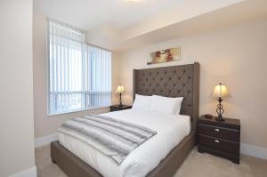 Un dormitorio con una cama grande y una ventana en Royal Stays Furnished Apartments - Square One, en Mississauga