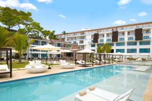 une piscine avec des chaises et des parasols en face d'un hôtel dans l'établissement Presidential Suites Cabarete - Room Only, à Cabarete