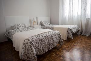 ログローニョにあるCon encanto y bien ubicadoの白い壁とウッドフロアのベッドルーム1室(ベッド2台付)