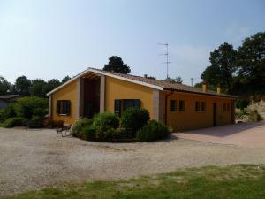 una pequeña casa amarilla con un banco delante en Agriturismo Dondino, en Cavriana