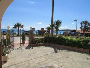 einen schmiedeeisernen Zaun mit Palmen und dem Meer in der Unterkunft Apartamentos Miramar in Bolonia