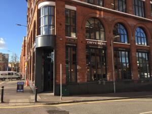 un edificio de ladrillo en una calle de la ciudad con un cartel delante en City Centre Belfast Free Parking, en Belfast