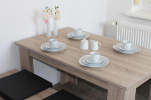 una mesa de madera con tazas y platillos. en 3 Zimmer Ferienwohnung - Woltorf, en Peine