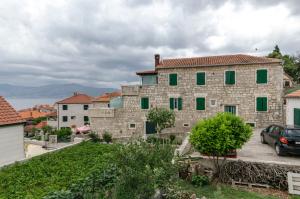 a large stone building with green shutters at Apartments Jurica in Postira