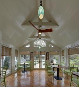a room with tables and chairs and a ceiling fan at The Grey Owl Inn in Saint Simons Island