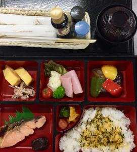 uma bandeja de alimentos com arroz e diferentes tipos de alimentos em Daymaruya Ryokan em Yamanouchi