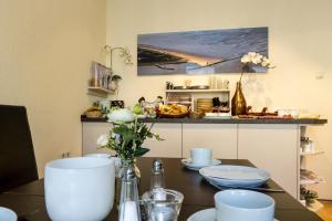 a kitchen with a table with plates and flowers on it at Pension Appartementhaus Hus Möhlenbarg in Cuxhaven +35 photos