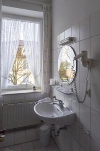 a bathroom with a sink and a mirror and a window at Pension Appartementhaus Hus Möhlenbarg in Cuxhaven