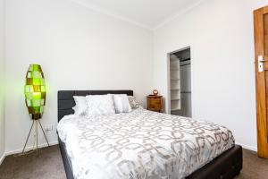 - une chambre avec un grand lit aux murs blancs dans l'établissement The Stonemason's Cottage, à Dunedin
