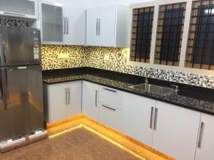 a kitchen with white cabinets and a stainless steel refrigerator at Luxury Villas of Guruvayur in Guruvāyūr