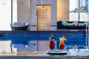 two cocktails sitting on a table next to a swimming pool at Duxton Hotel Perth in Perth