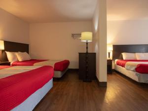 a hotel room with two beds and a lamp at Best Budget Inn & Suites Kamloops in Kamloops