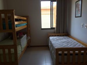 a bedroom with two bunk beds and a window at Village Duplex Confortável e Acolhedor junto a Natureza - Condomínio Reserva das Ilhas in Itacimirim