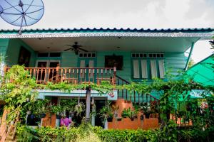 ein grünes Haus mit einem Balkon und einem Ventilator in der Unterkunft Samsen Sam Place in Bangkok