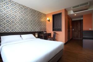 a bedroom with a white bed and a wall at Rambuttri Village Plaza - SHA Extra Plus in Bangkok