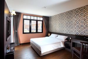 a bedroom with a large bed and a window at Rambuttri Village Plaza in Bangkok