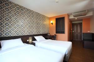 a hotel room with two beds and a wall at Rambuttri Village Plaza in Bangkok