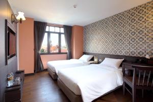 a hotel room with two beds and a window at Rambuttri Village Plaza in Bangkok