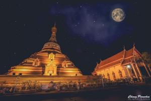 een groot houten gebouw met een maan op de achtergrond bij Baan Din Baramee Resort in Kamphaeng Phet