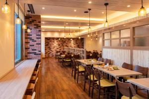 a restaurant with tables and chairs and a brick wall at Hotel Resol Sapporo Nakajima Koen in Sapporo